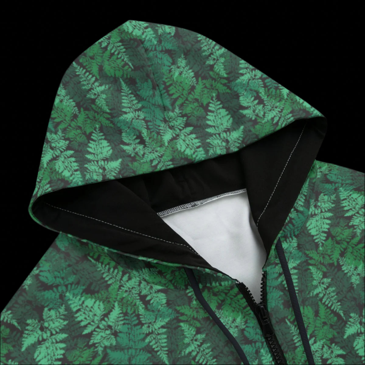 Front top of a green leafy patterned zipper hoodie on a black background