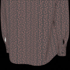 Bottom back hem of a long sleeved patterned shirt on a black background